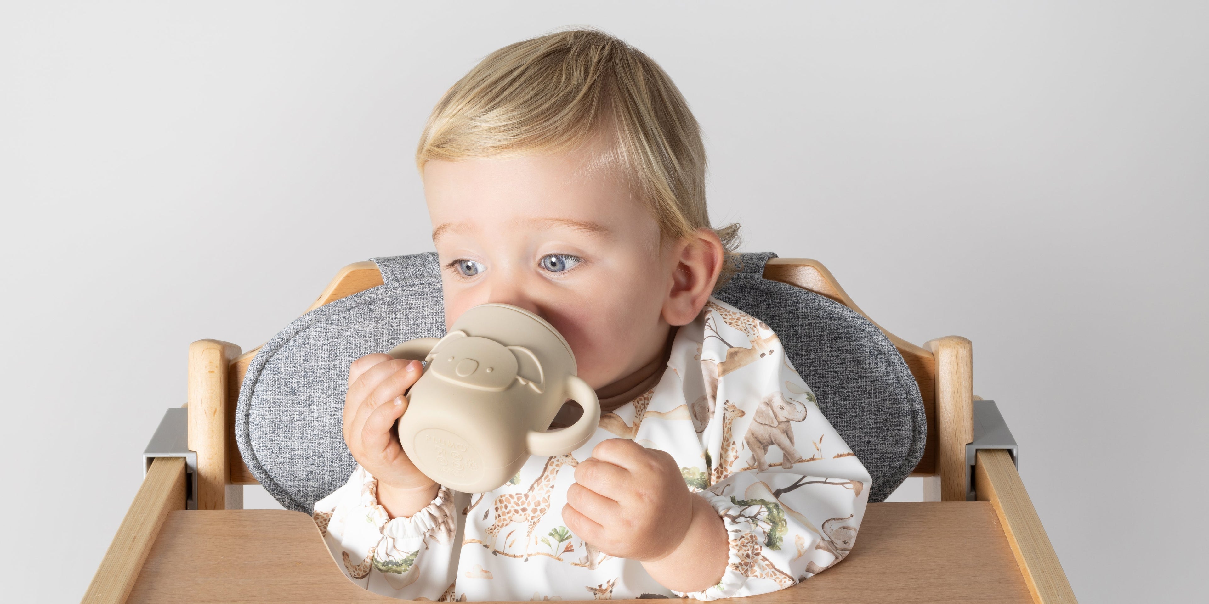 baby in high chair with koala silicone sippy cup, bib and plate