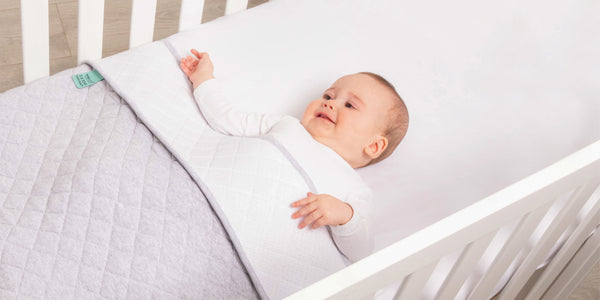 baby in cot using a sleep pouch