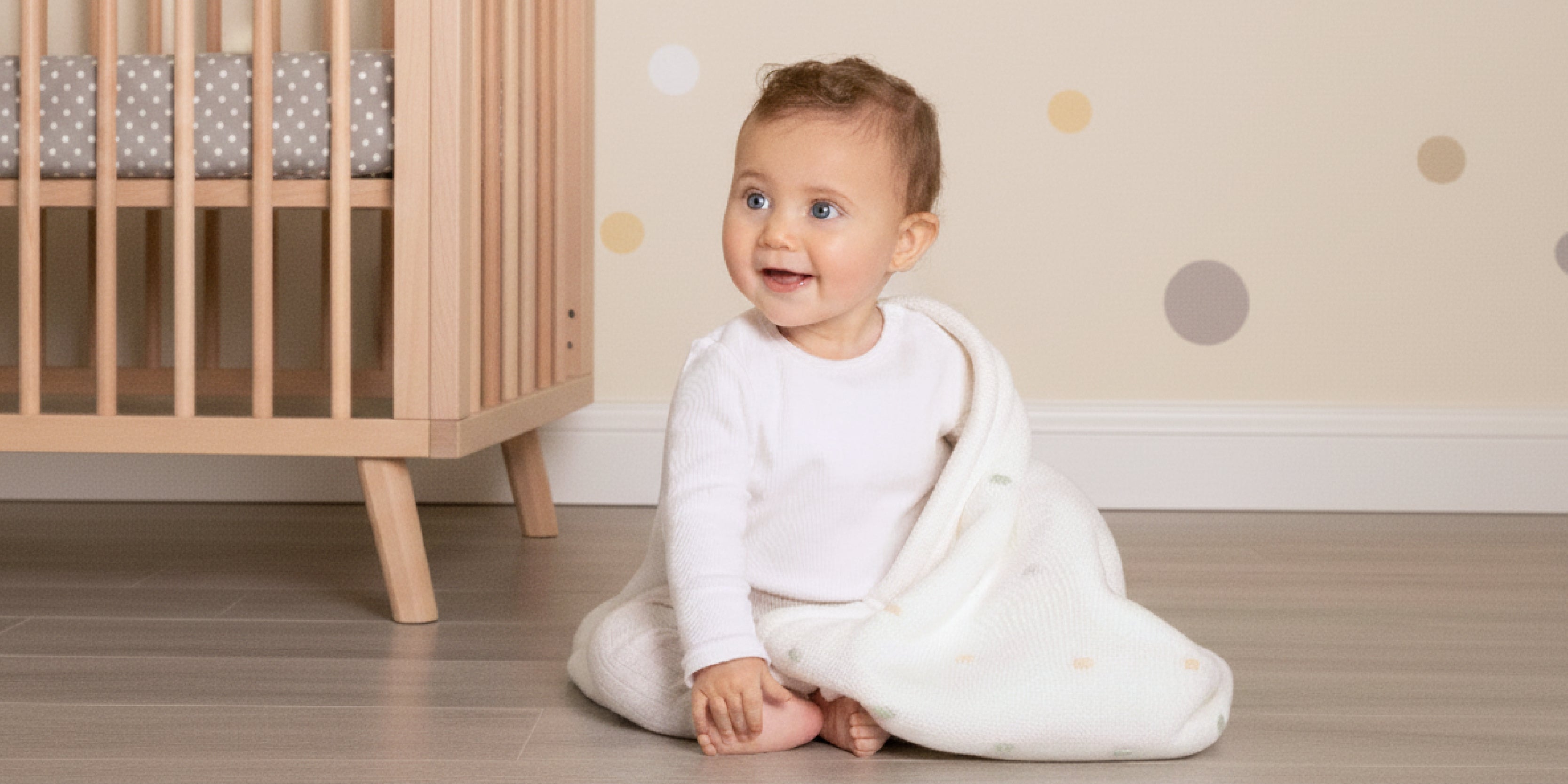 happy baby in basket of polkadot blankets wraps and sheets